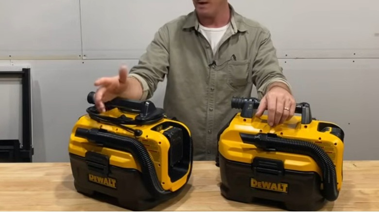 Person displaying two DeWalt shop vacuums on a table
