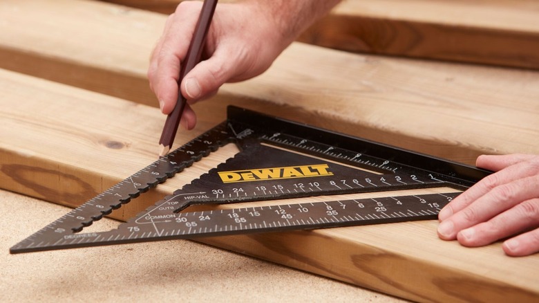 Person using DeWalt Quick Square to make measurements on wood with a pencil