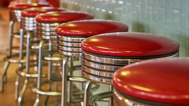A row of chrome metal stools with red seats at a counter.