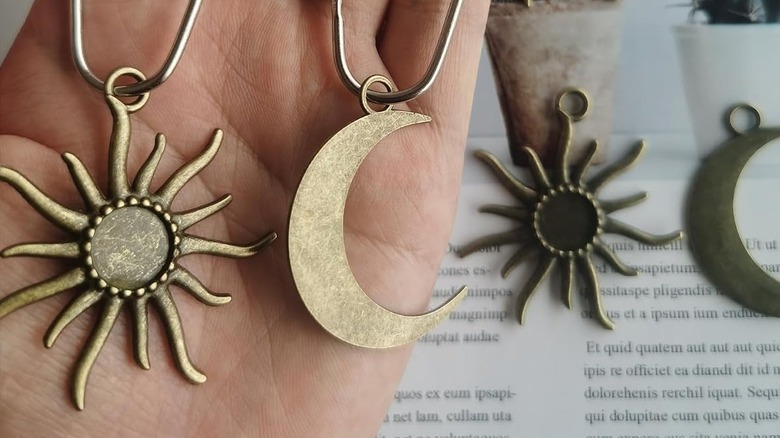 A hand holding a moon and a sun shower charm on the hooks, with more in the background