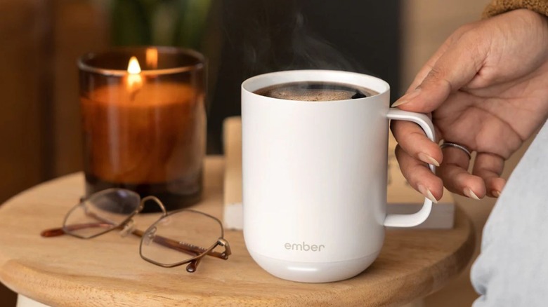 Ember cup filled with coffee sitting on a table with a candle
