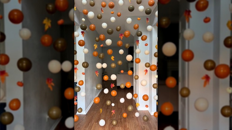 Hanging balloon decor with fall colors with leaves and mini pumpkins in a hallway
