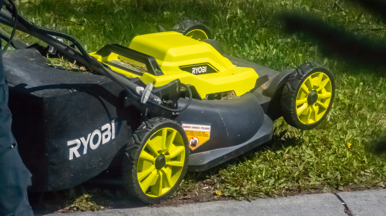 Close-up of a gardener pushing a Ryobi lawn mower