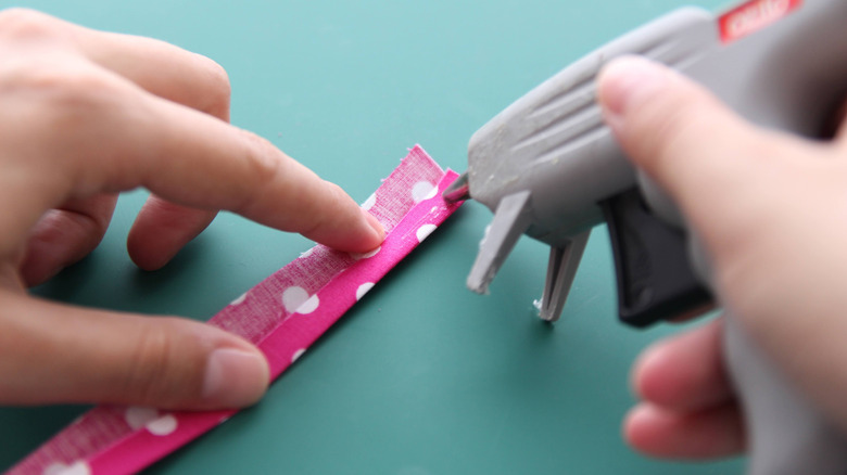 Two hands work at gluing fabric trim.