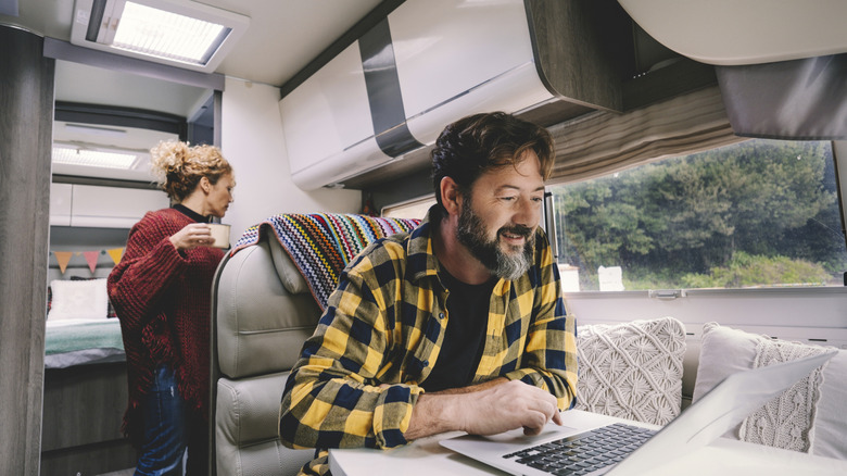 A couple inside of their RV, with the man working on a computer
