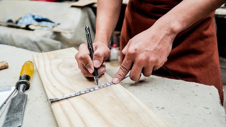 Person measuring wood in a workshop