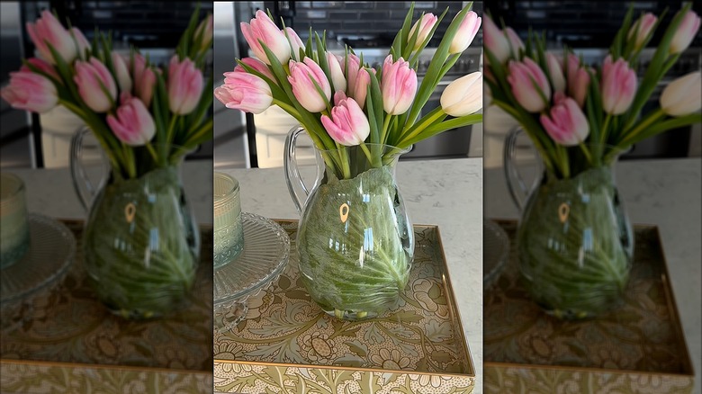 Pink flowers in glass vase lined with cabbage leaves