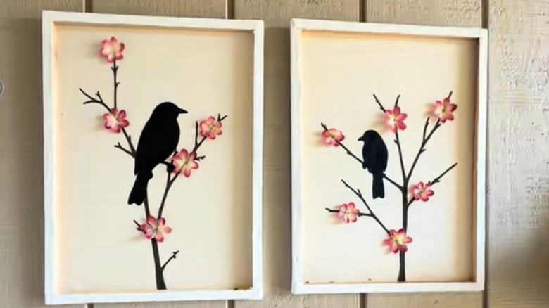 Canvases decorated with black bird silhouettes on branches topped with glued-on flowers