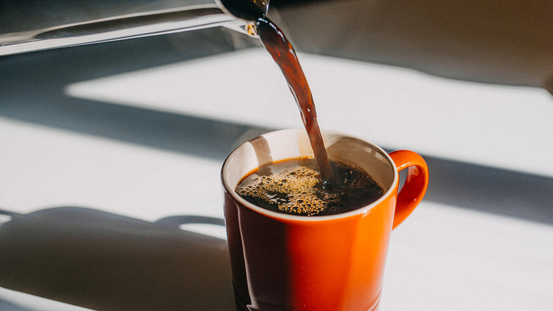 Closeup of coffee being poured into an orange mug