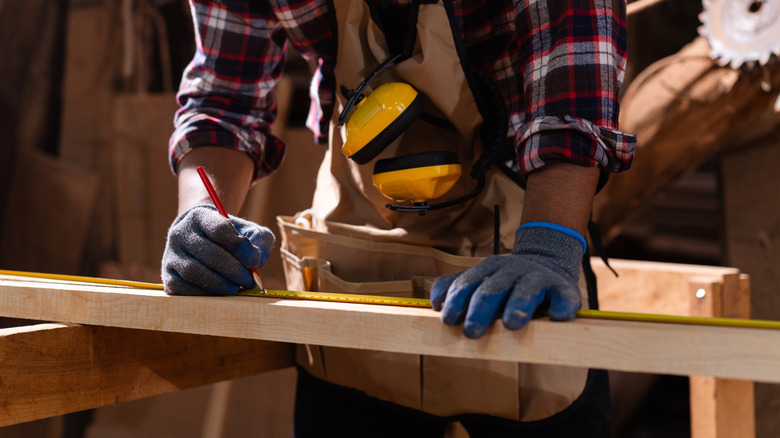 A man measuring wood with a tape measure
