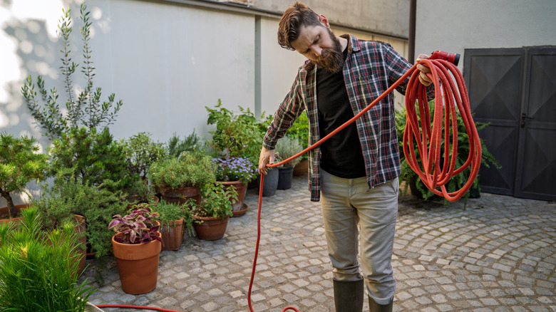 a man wrapping up a garden hose for storage