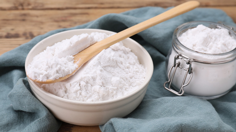 Bowl of cornstarch and jar on a blue cloth on top of a wooden table