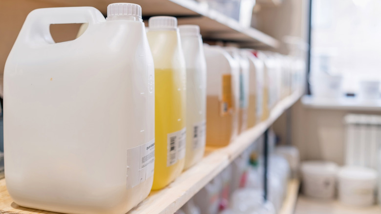 a row of large plastic detergent containers on a supply shelf