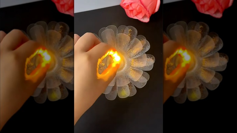 Person inserting candle into plastic bottle lotus flower