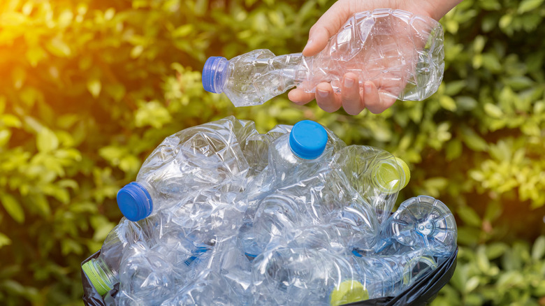 Person grabbing an empty water bottle from a pile