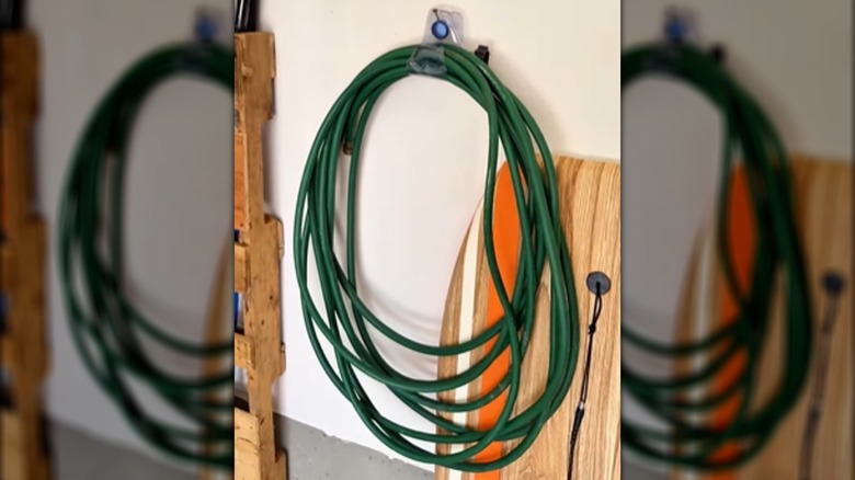 blue garden hose mounted on hose hook on the side of a house
