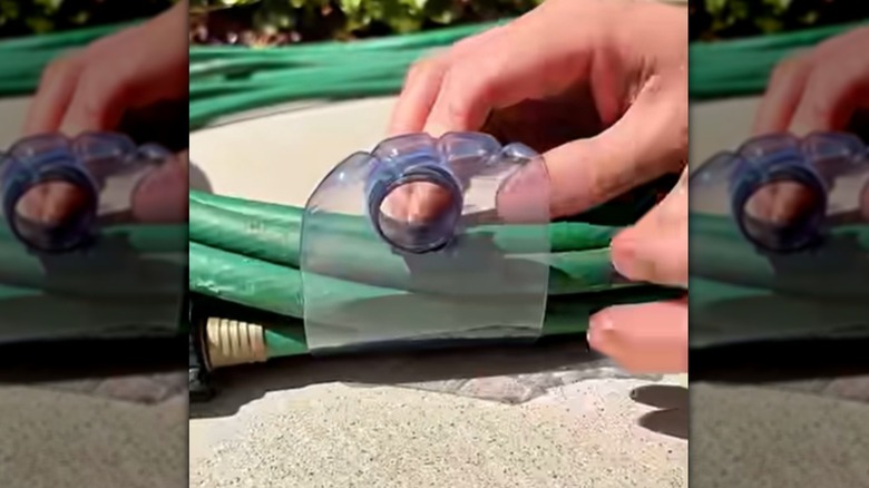 Someone wrapping a cut plastic water bottle around a hose.