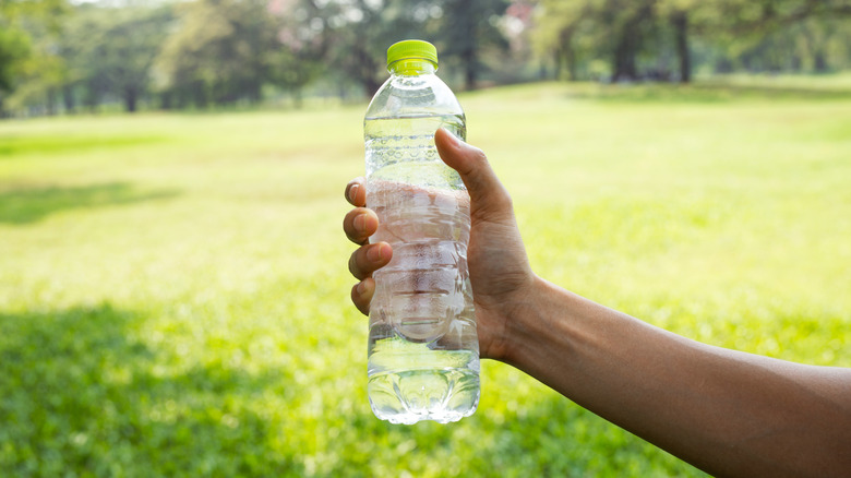 A person holding a plastic water bottle outdoors