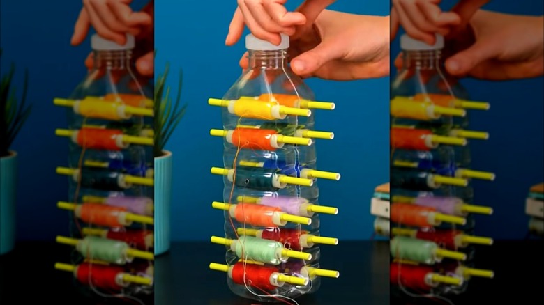 A plastic water bottle repurposed as a thread dispenser.