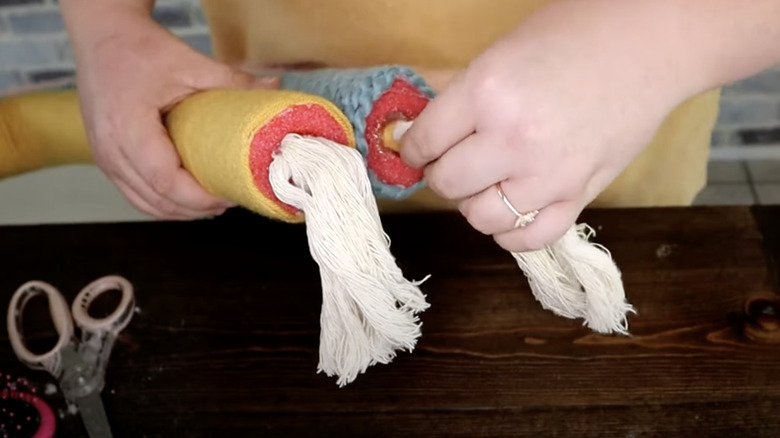 Person adding tassels to macrame pool noodles