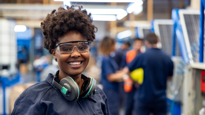 Woman wears protective safety goggles and gear while smiling at the camera