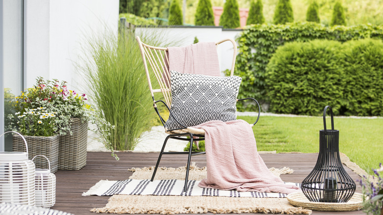 An outdoor pillow placed on a chair on a back patio space
