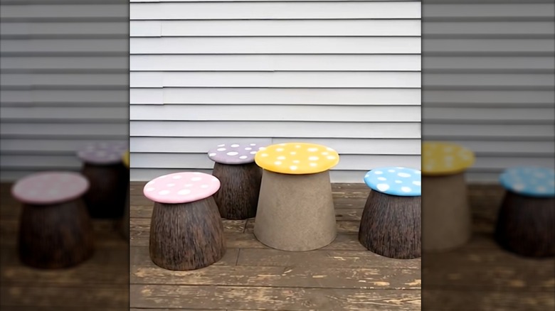 DIY mushrooms made from painted wood rounds and upturned planters arranged on a backyard deck.