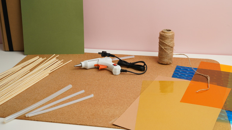 Craft supplies including hot glue, skewers, string, and colored paper.