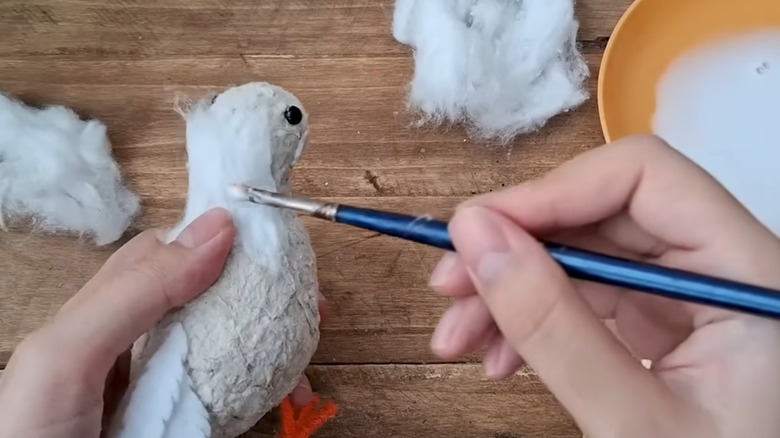 Adding the cotton to the bird by gluing it in torn layers.