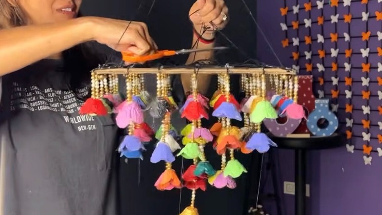 A hang cutting a colorful piece of hanging flower decor.