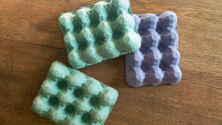Three colorful egg cartons on a wood table.