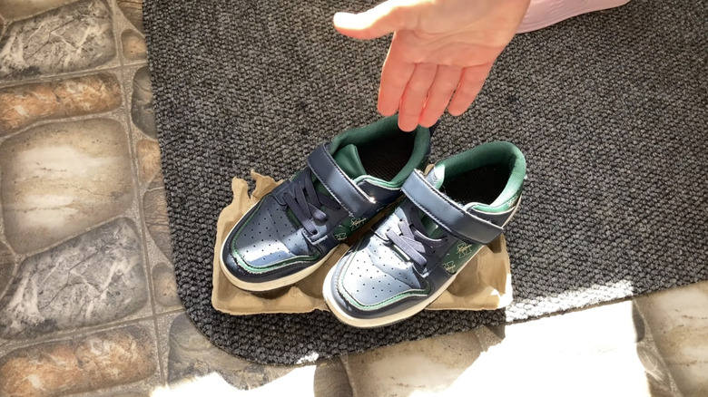 Person holding out their hand to show their DIY project of an egg carton with sneakers placed on top