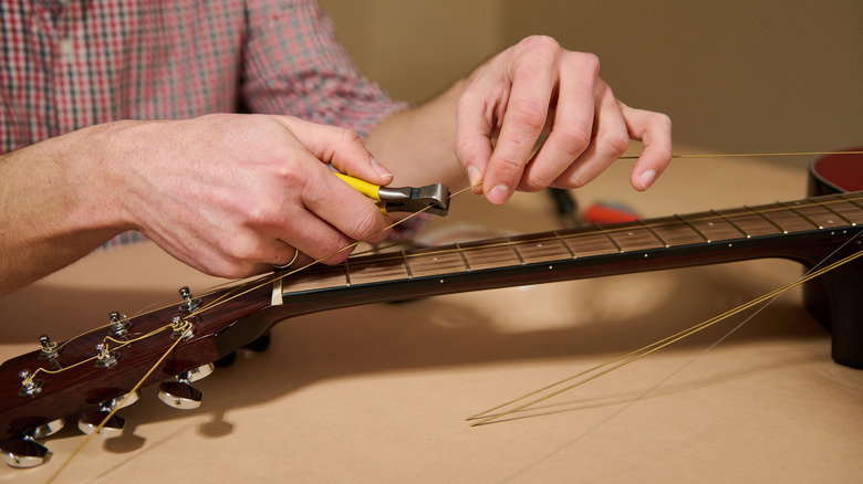 Someone cutting the strings off a guitar