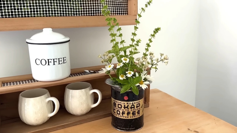 A thrifted vintage coffee tin acts as a flower vase on a coffee bar