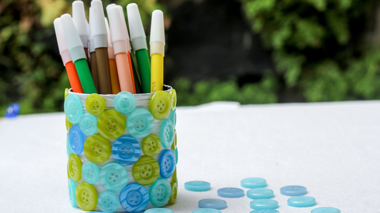 Plastic bottles cut in half and decorated to be pen holders.