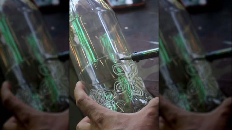 A person applying a soldering iron to plastic bottle for design