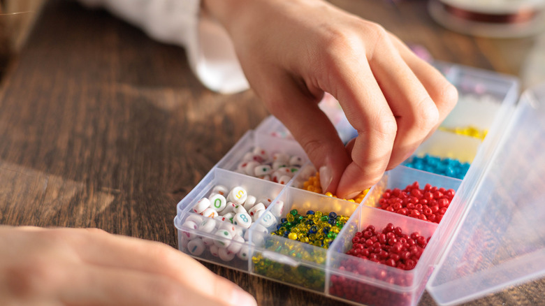a person's hands picking out loose beads for a project