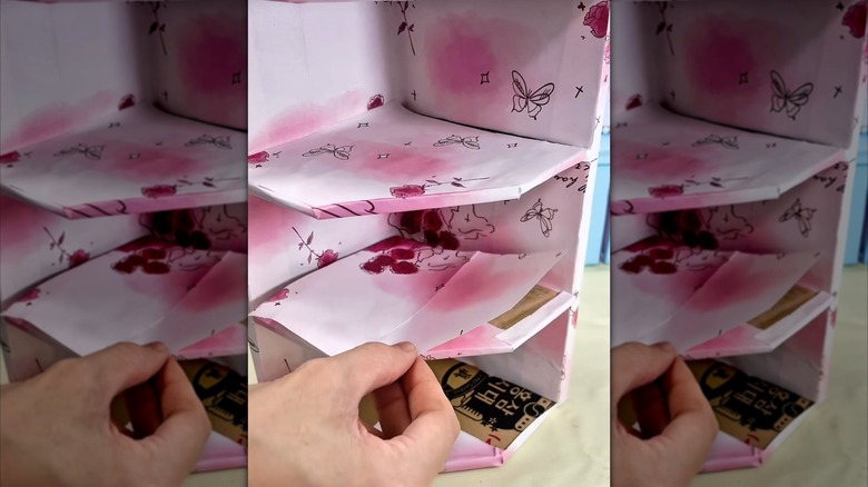 A DIY shelf made with cardboard scraps and decorated with paper.