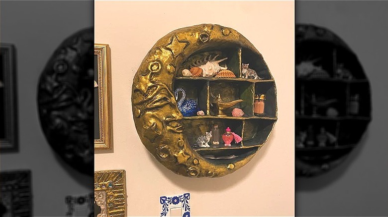 A moon shelf handmade from cardboard, clay, and paper mache painted gold.