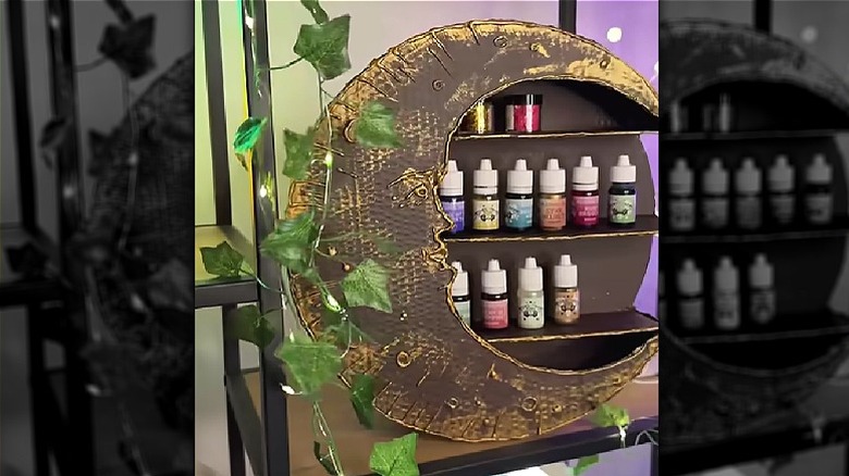 A moon-shaped shelf made from cardboard with essential oil bottles displayed.
