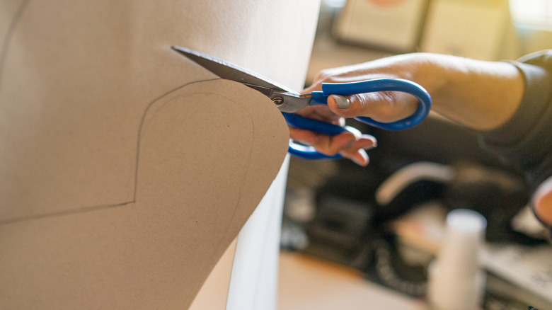 A person cutting cardboard with scissors