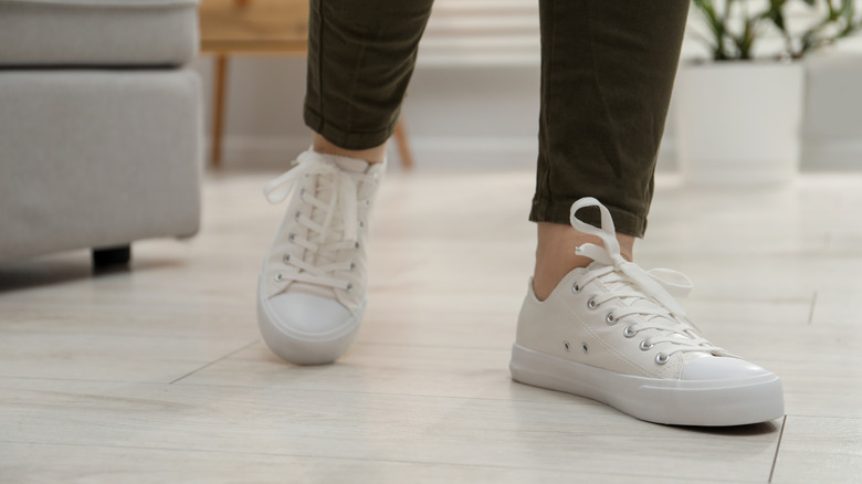 Person wearing white sneakers walks on vinyl flooring