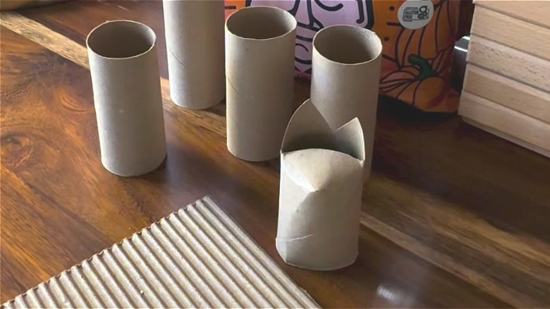 Toilet paper tubes beside corrugated cardboard on a table, one of which is folded into a bat shape.