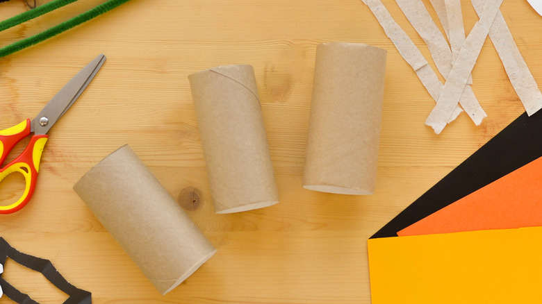 Three toilet roll tubes on a table amongst other craft supplies.
