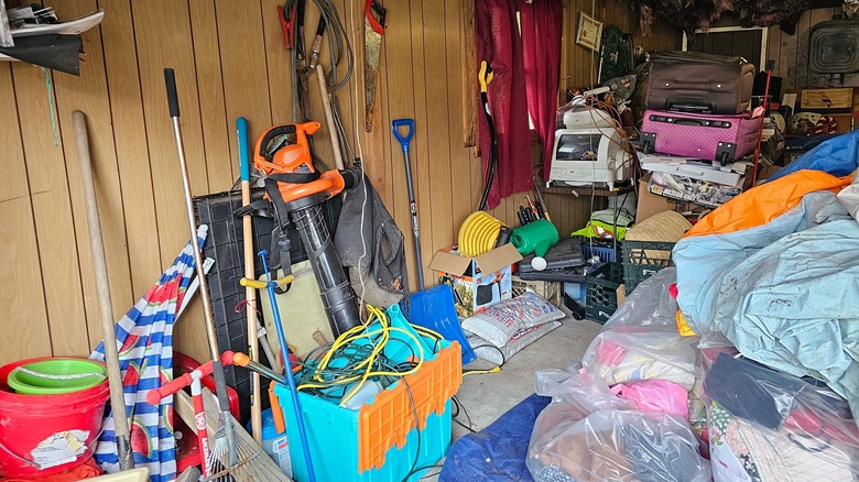 A messy garage with long-handled tools just leaning against a wall