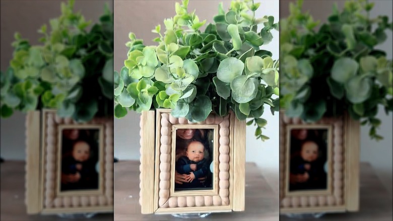 A DIY spinning picture frame planter holds artificial greenery.