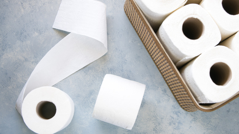 rolls of toilet paper in basket and on countertop