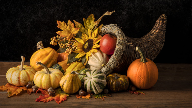 A cornucopia-shaped fall centerpiece with pumpkins