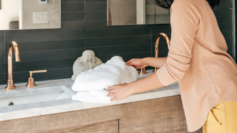Woman in large bathroom with towel and some beauty products on the counter