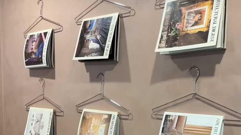 Architectural Digest magazines displayed on metal hangers in rows on a wall